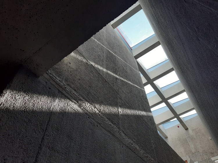 Een zicht op de betonnen muren en glazen dak van het museum.