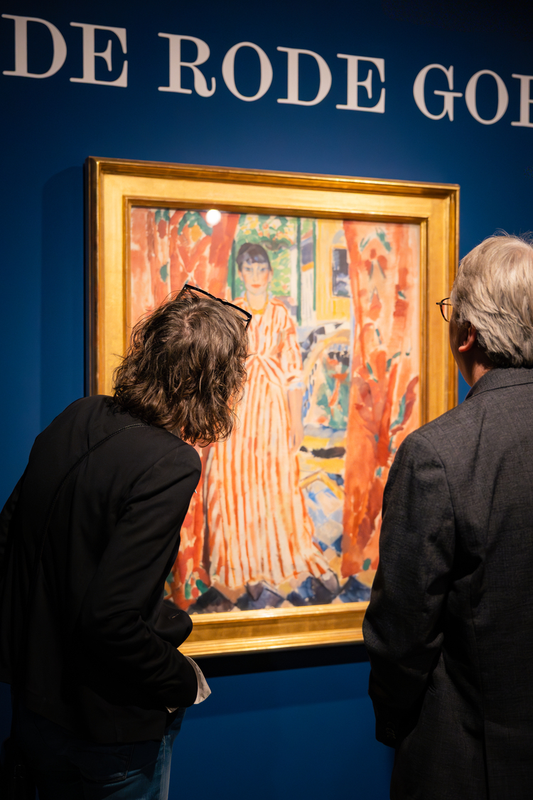 Twee mensen kijken naar een schilderij van een vrouw in rood wit gestreepte jurk.